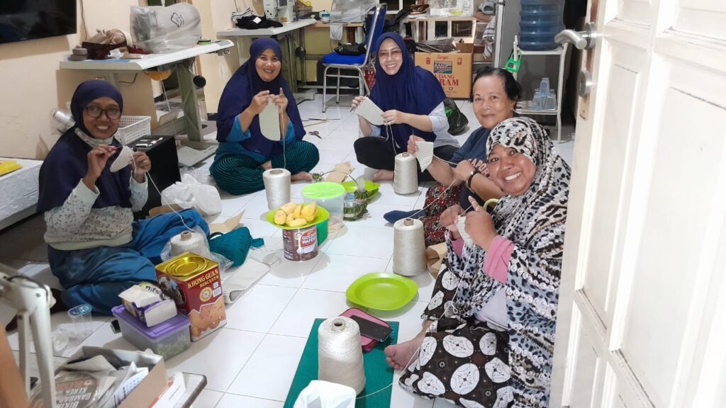Tinggalkan Karier Demi Impian: Sukses Yuni SA dalam Dunia Kerajinan Rajut Yuni Suwanti Asih atau yang akrab dipanggil June SA hijab biru tua berkacamata tengah, saat bersama pengerajin rajut di kediamannya Pondok Sidokare Indah, Sidoarjo,Rabu(4/9/2024)(Foto: Dian/Etara.id).